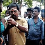 Extremist with ash mark of Hindu devotion on his forehead checks phone after stopping children going to Vacation Bible School in Ratnapuri, India. (Morning Star News)