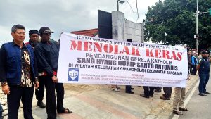 Muslim residents with banner saying they reject construction of Catholic church building in Cipamokolan village, Indonesia. (Porosmedia.com)